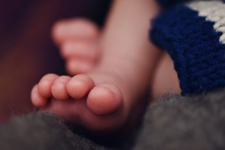 Zwei kleine Babyfüße auf einem weichen, grauen Untergrund.