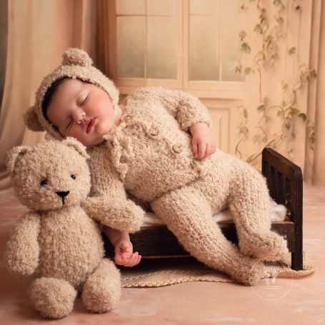 Schlafendes Baby in Bärenkostüm, umarmt einen plüschigen Bären.