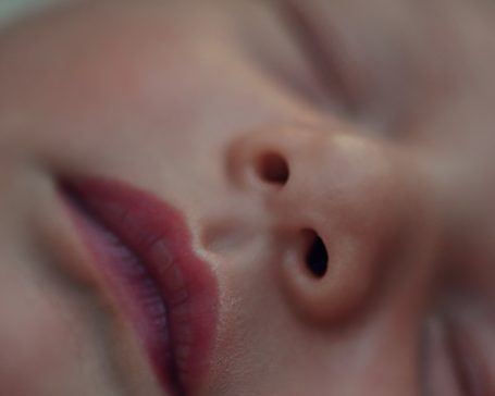 Nahaufnahme des Gesichts eines schlafenden Babys mit geschlossenen Lippen und kleinen Nasenlöchern.